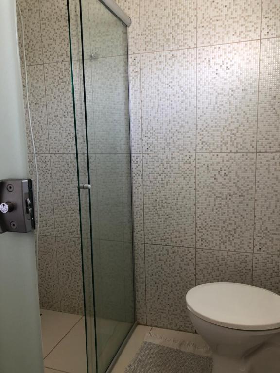 uma casa de banho com um WC e uma cabina de duche em vidro. em Villa Interlagos de Minas em Guapé