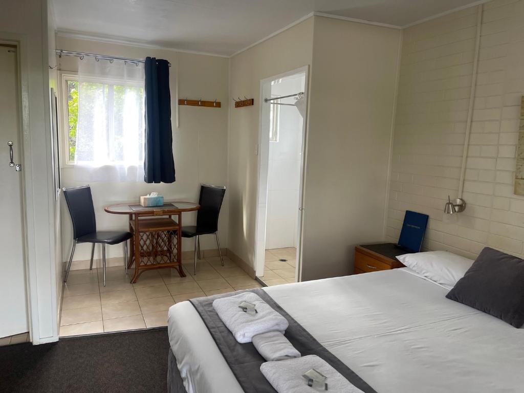 a bedroom with a bed and a table with chairs at Avocado Motor Inn in Childers