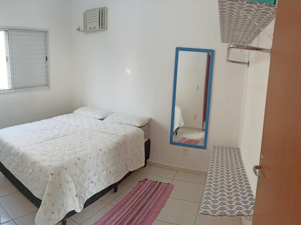 a white bedroom with a bed and a mirror at Apartamento inteiro próximo à Miguel Sutil in Cuiabá