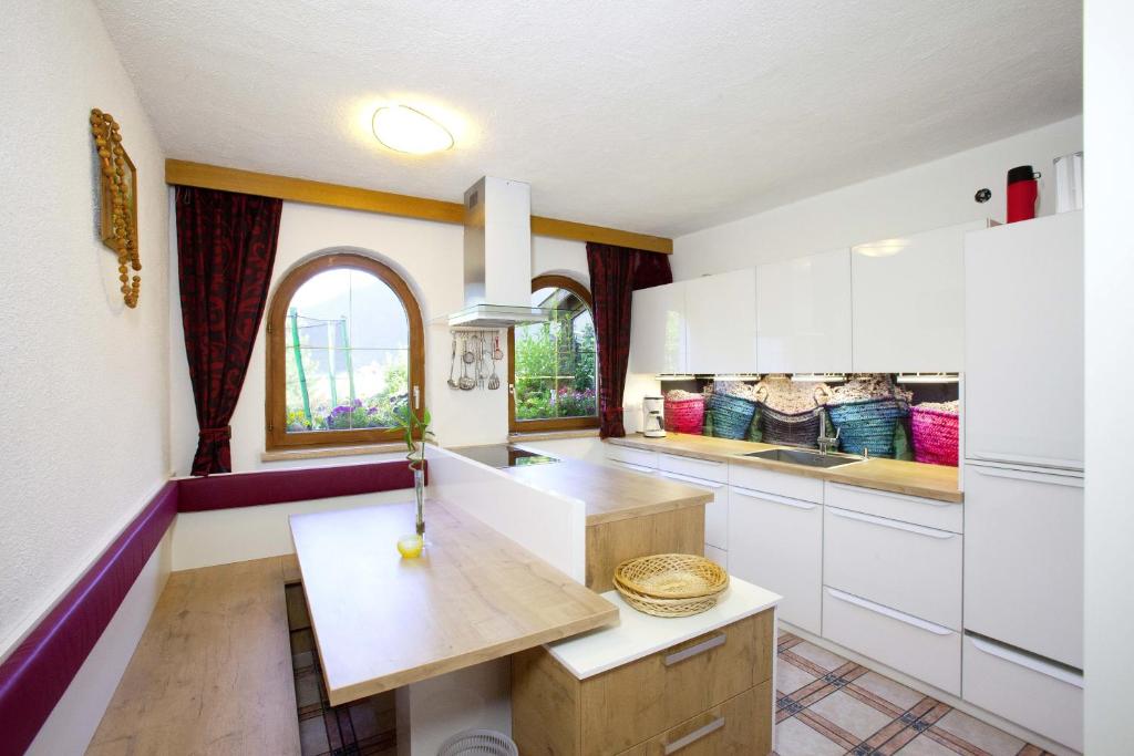 a kitchen with white cabinets and a wooden table at Familienferienhaus Florentine in Längenfeld