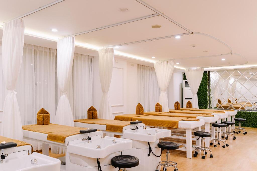 a room with tables and chairs and white sinks at Happy Day Riverside Hotel & Spa Danang by Haviland in Danang