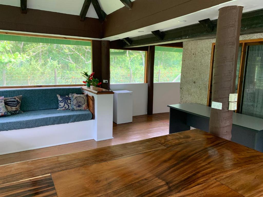 a living room with a couch and large windows at Fiji Fishing Holiday Bure in Savusavu