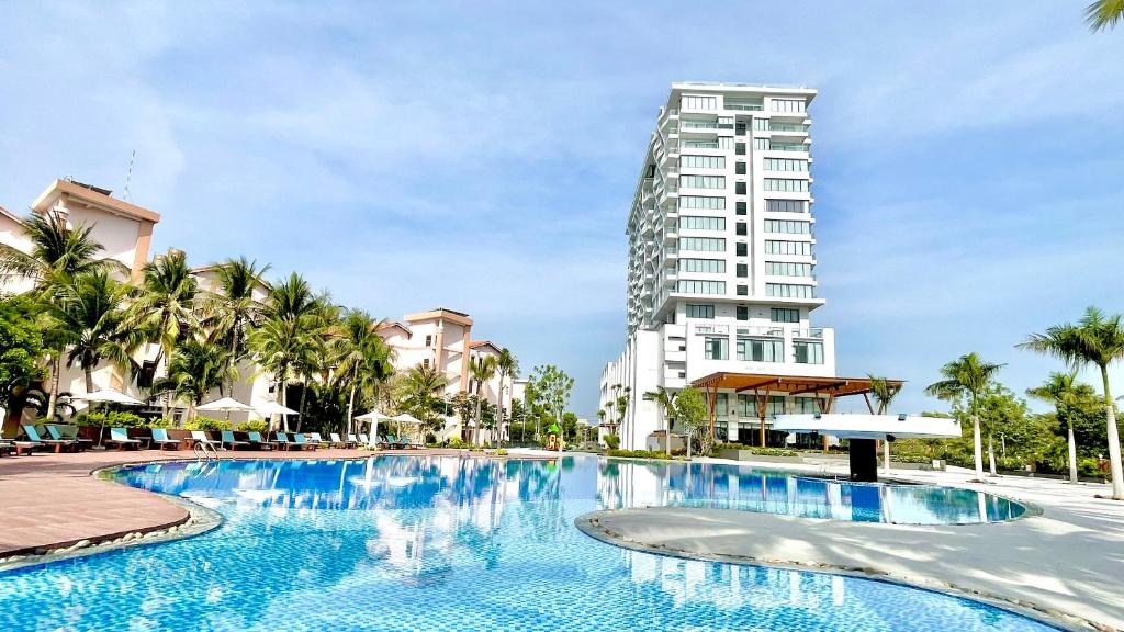 Long Thuan Hotel & Resort في فان رانغ: حمام سباحة كبير مع مبنى طويل في الخلفية