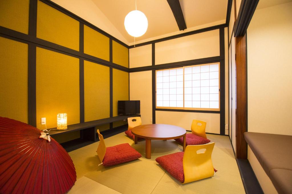 une pièce avec une table, des chaises et une fenêtre dans l'établissement ゲストハウス京都ミルズ紅藤庵, à Kyoto