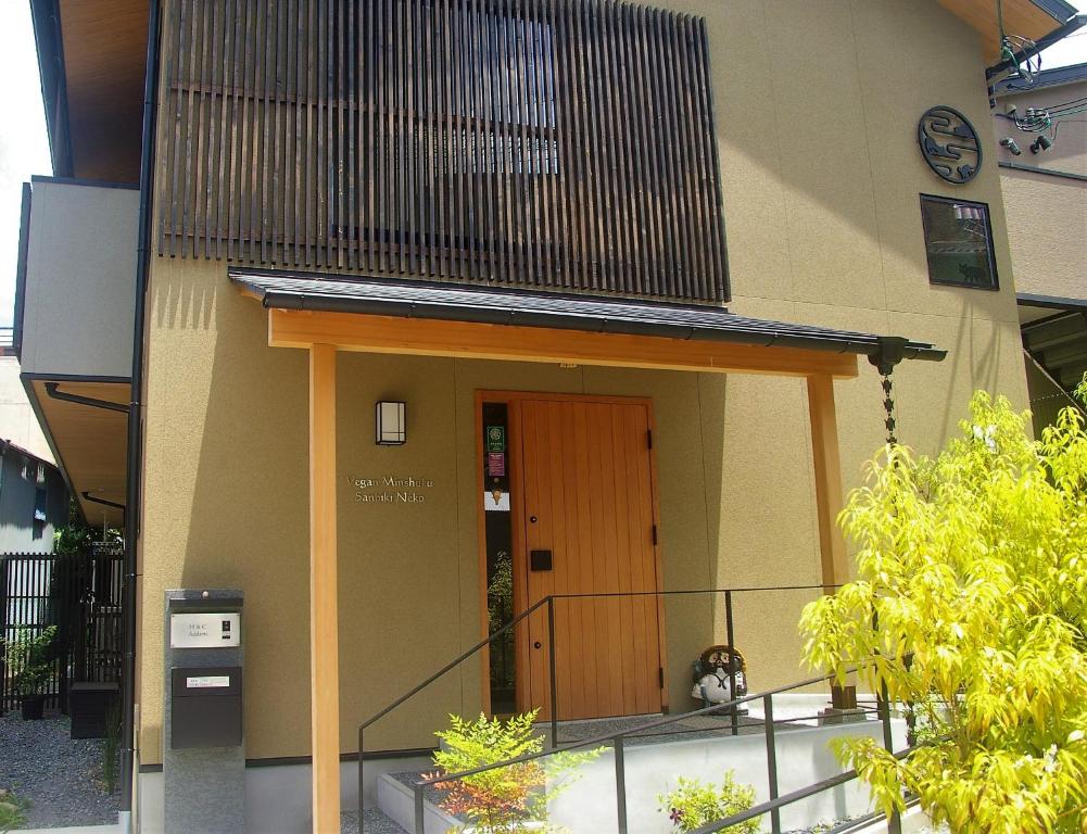 a building with a brown door and a balcony at Vegan Minshuku Sanbiki Neko in Kyoto