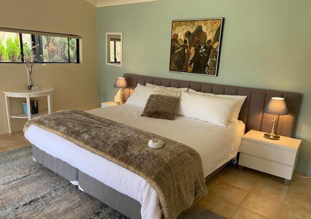 a bedroom with a large bed and a painting on the wall at Granite Gardens Cottages & Lake Retreat in Stanthorpe