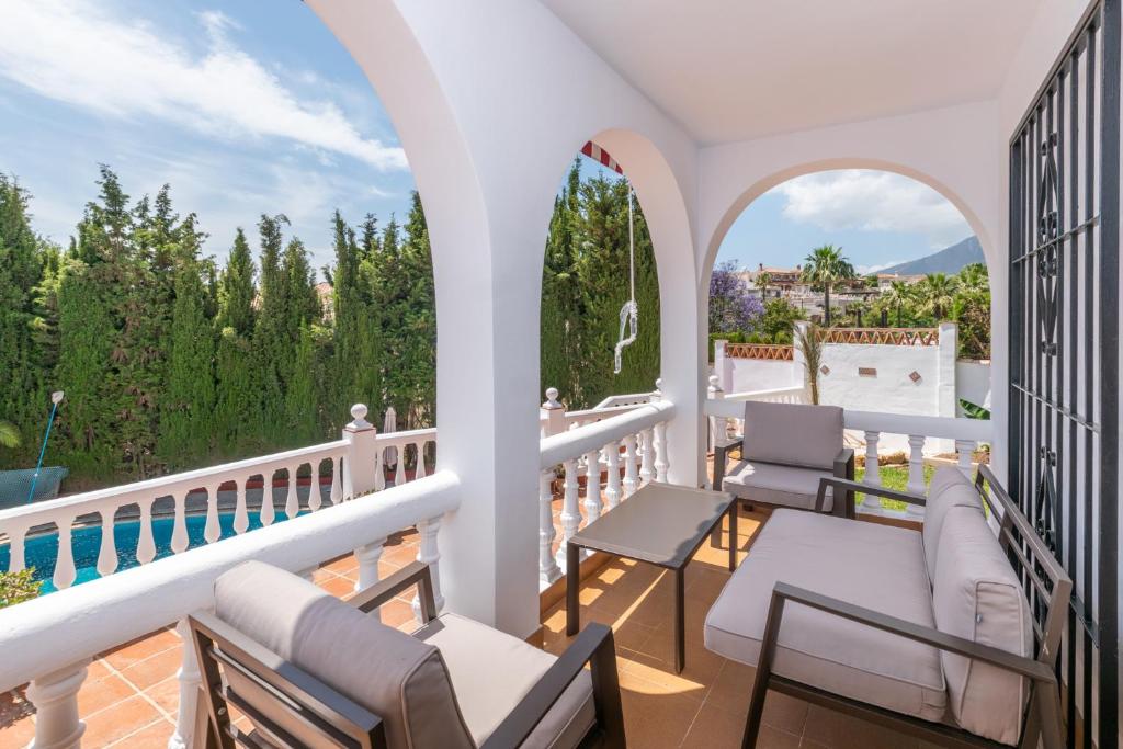 Cette chambre dispose d'un balcon avec des chaises et une piscine. dans l'établissement VILLA ALEGRIA Big terrace, private pool & parking, à Mijas