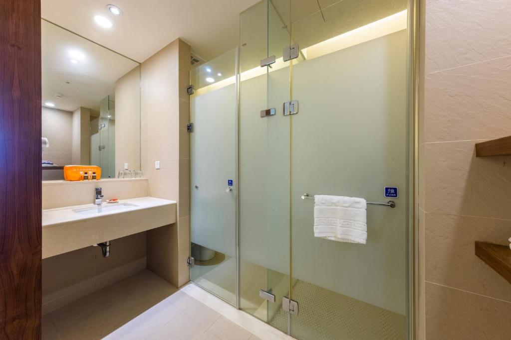 bagno con doccia in vetro e lavandino di South Garden Hotels And Resorts a Zhongli