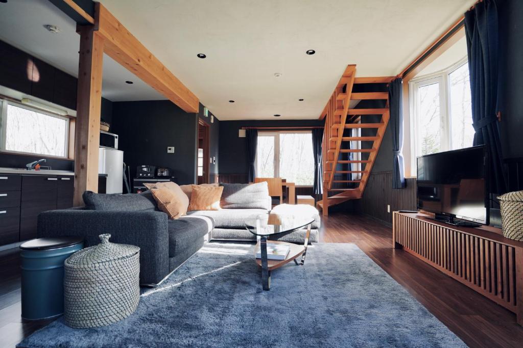 a living room with a couch and a stair case at Goodfellas Onsen House in Niseko