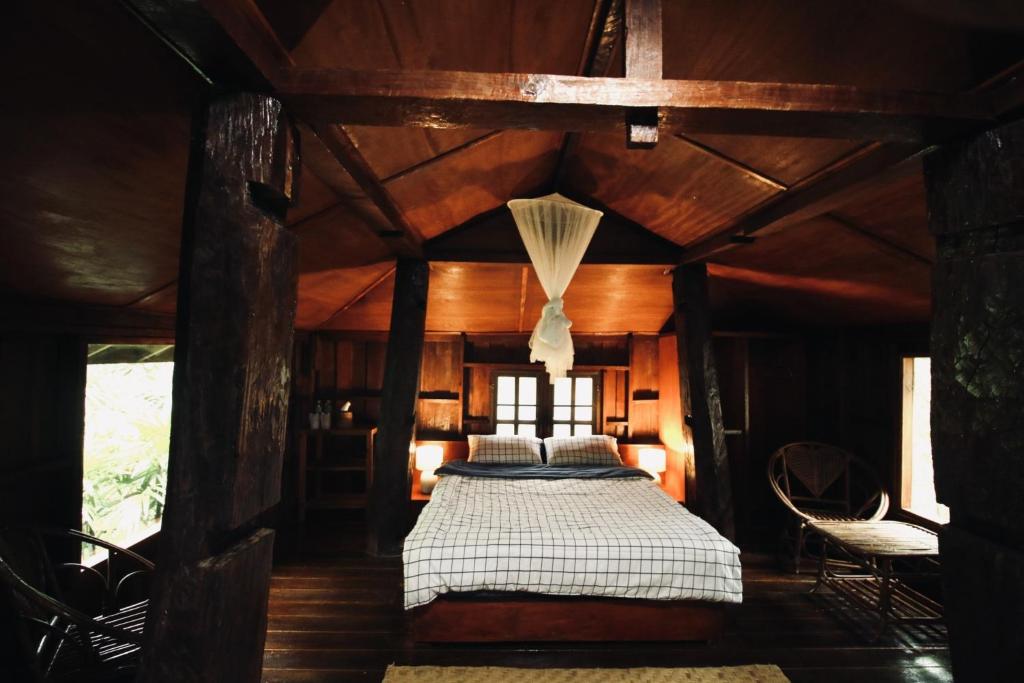 a bedroom with a bed in a room with wooden ceilings at Khoom Kam Kaew in Phrao