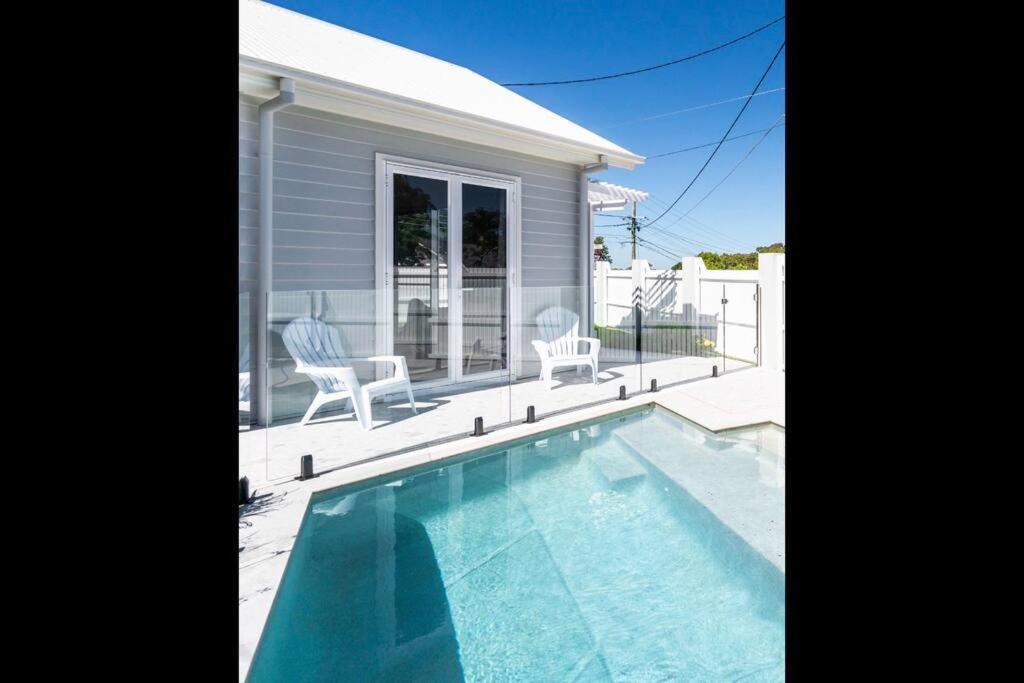 uma piscina com duas cadeiras e uma casa em Cute annexe - close to Manly Marina em Brisbane