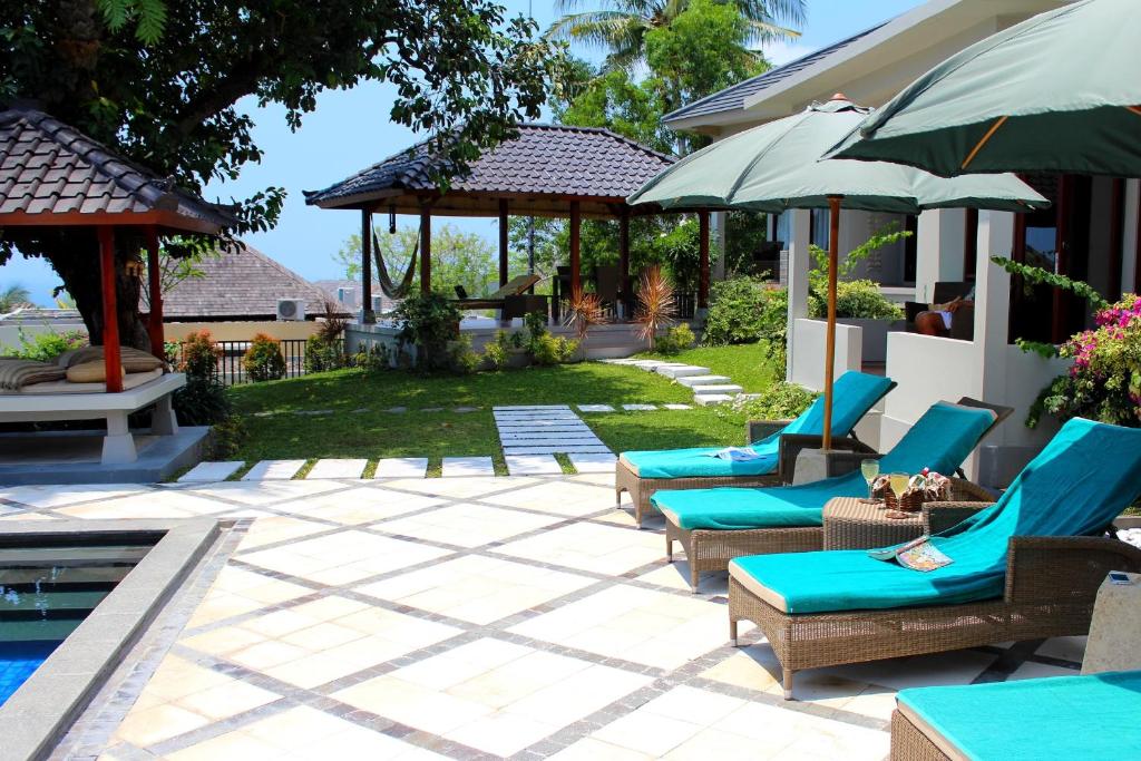a patio with chairs and umbrellas next to a house at Villa Karingal in Senggigi