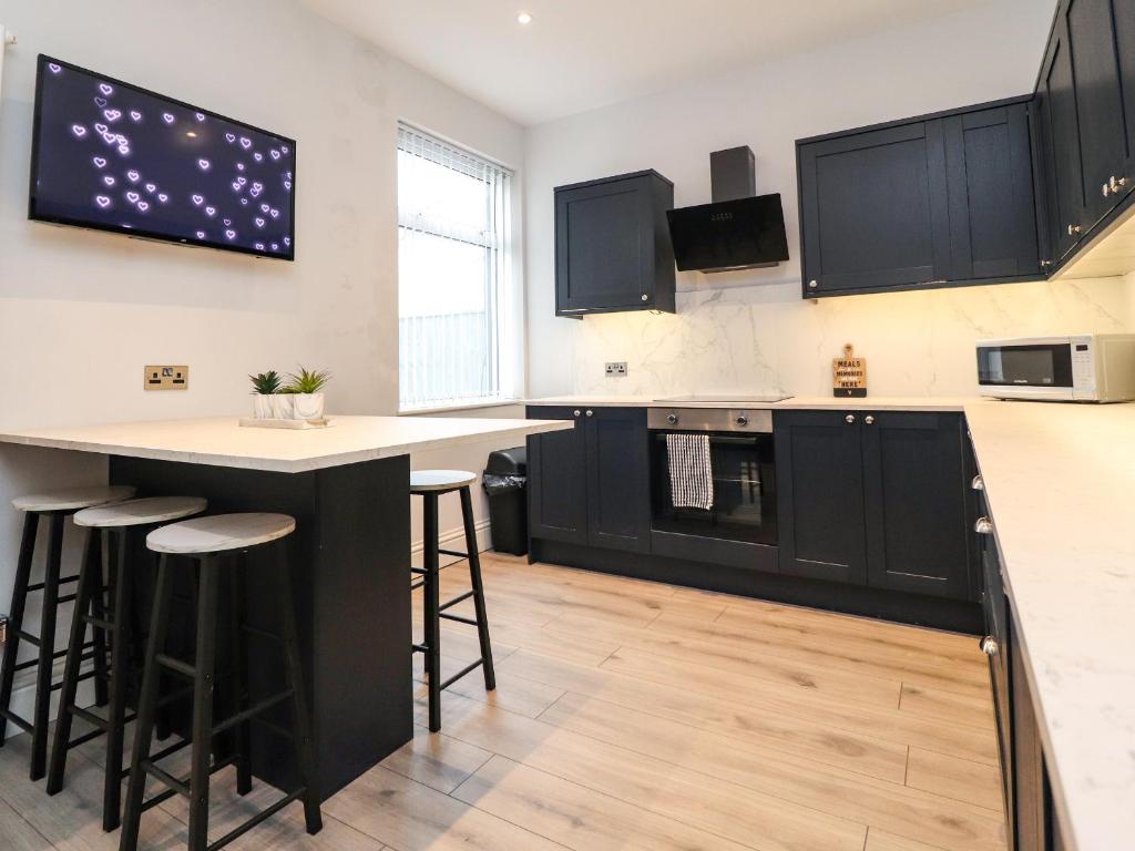 a kitchen with black cabinets and a bar with stools at 37 Nutter Road in Cleveleys