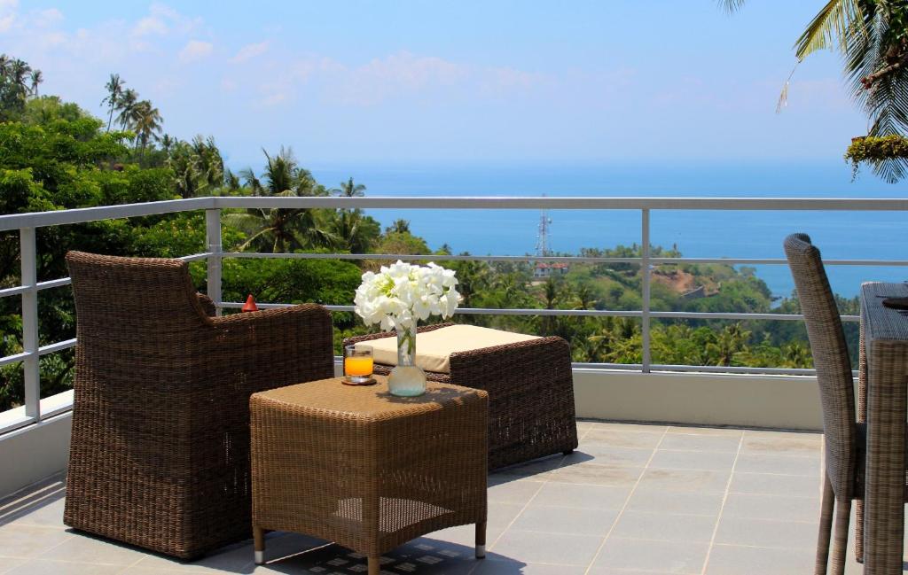 a balcony with chairs and a table with a vase of flowers at Villa Karingal in Senggigi