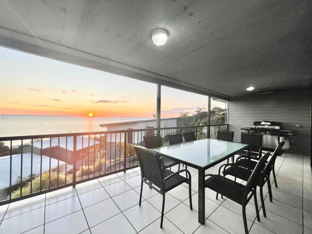 una mesa y sillas en un balcón con vistas al océano en Sunsets on Moreton 5 Ramosus, en Tangalooma