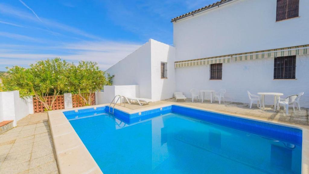 a swimming pool with blue water in front of a house at El Garrotal - El Pan El Bosque by Ruralidays in El Bosque