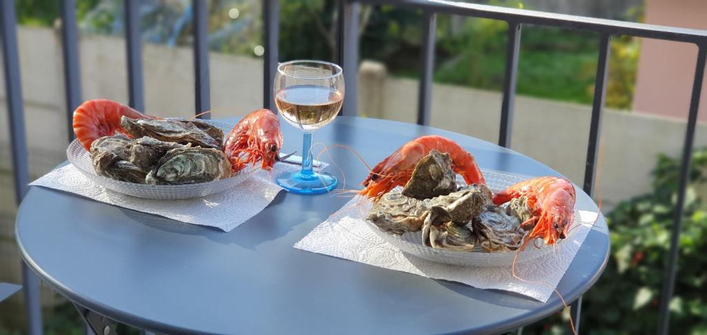 a table with two lobsters and a glass of wine at Colibri Appart&#39; T2 au coeur du Bassin d&#39;Arcachon in Gujan-Mestras