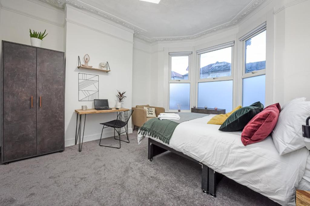 a bedroom with a bed and a desk and windows at Private Room in a Shared Accommodation in Norwood