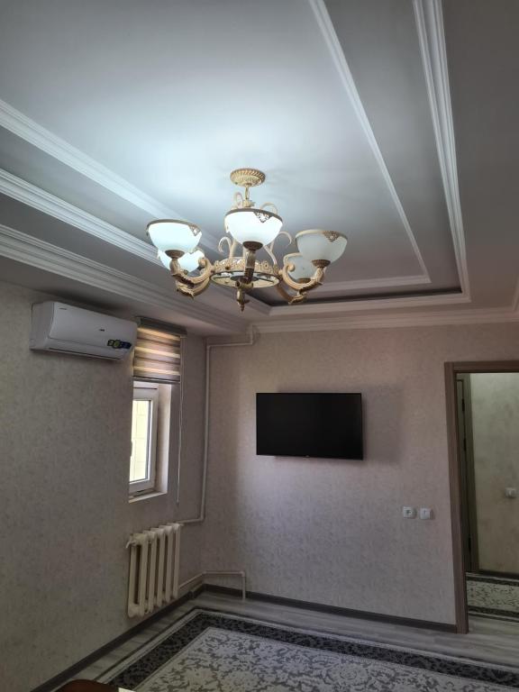 um tecto com um lustre e uma televisão num quarto em 3-х комнатная аппартамент em Tashkent