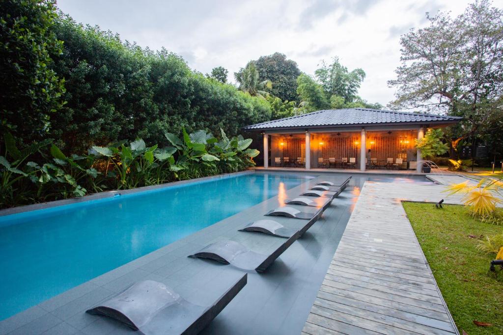 a swimming pool with lounge chairs next to a house at The Henry Resort Dumaguete in Dumaguete