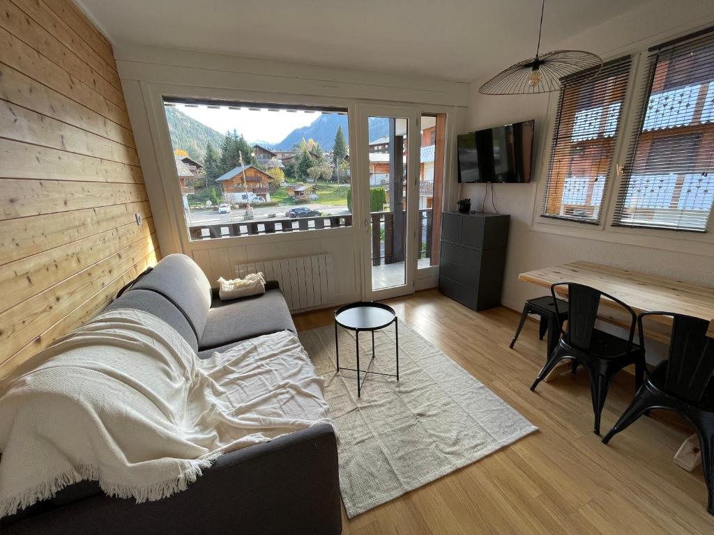 uma sala de estar com um sofá e uma mesa em Bel appartement rénové, central et skis aux pieds em Morzine