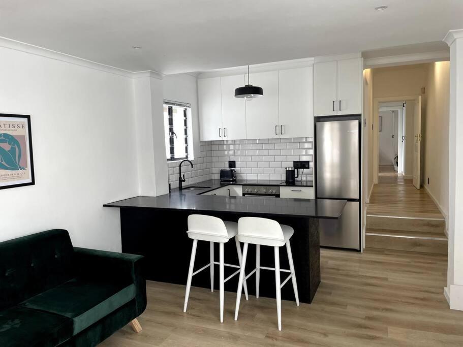 una cocina con encimera negra y taburetes en Centrally located modern 2-bedroom home & parking, en Ciudad del Cabo