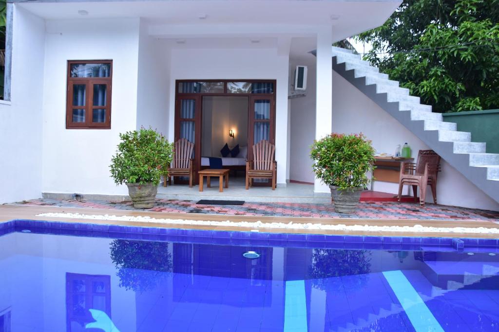 a villa with a swimming pool in front of a house at Ceylon Relax Villa in Moragalla