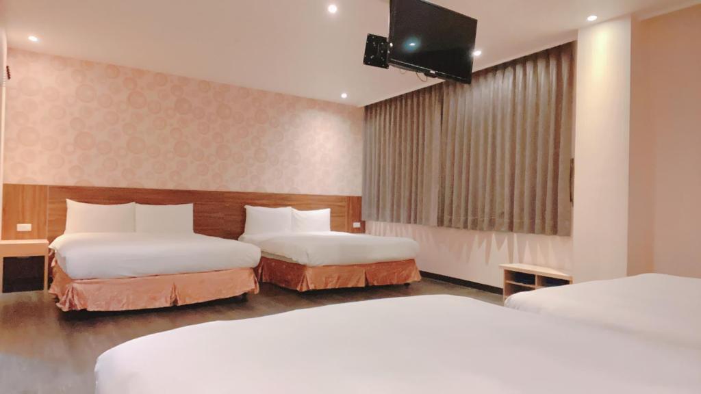 a hotel room with two beds and a flat screen tv at Centre Hotel in Kaohsiung