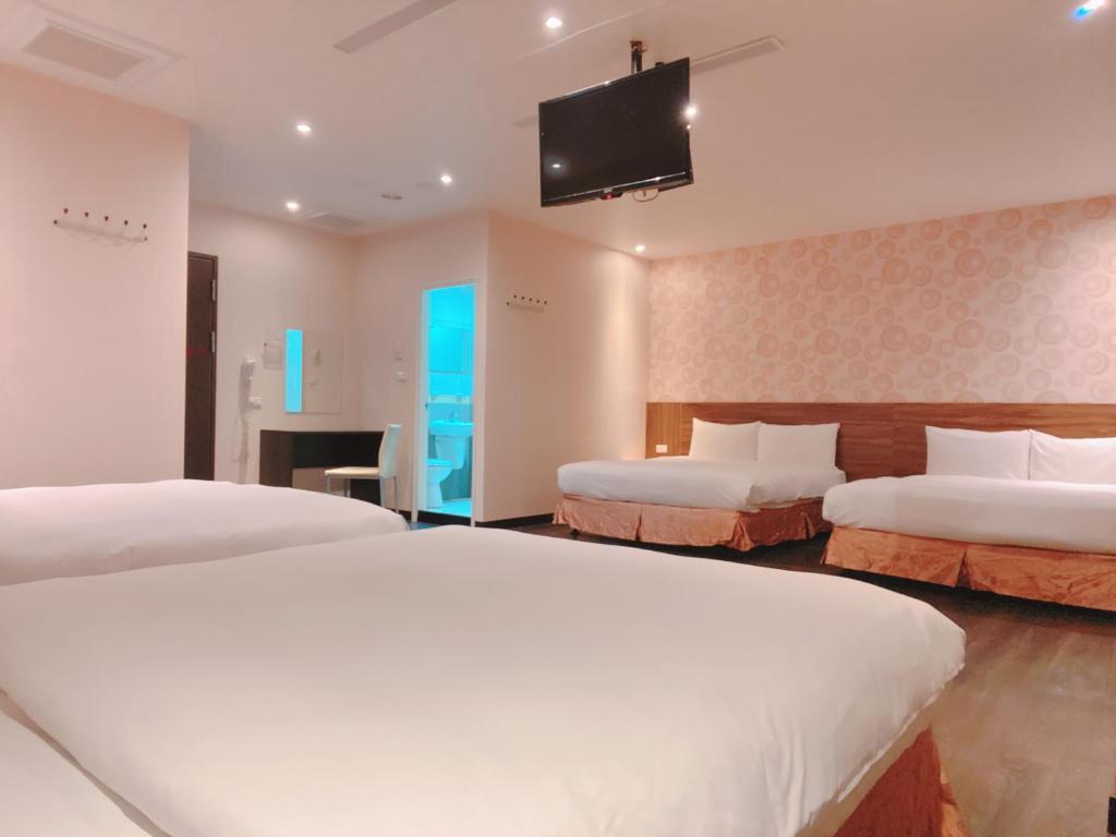 a hotel room with two beds and a flat screen tv at Centre Hotel in Kaohsiung