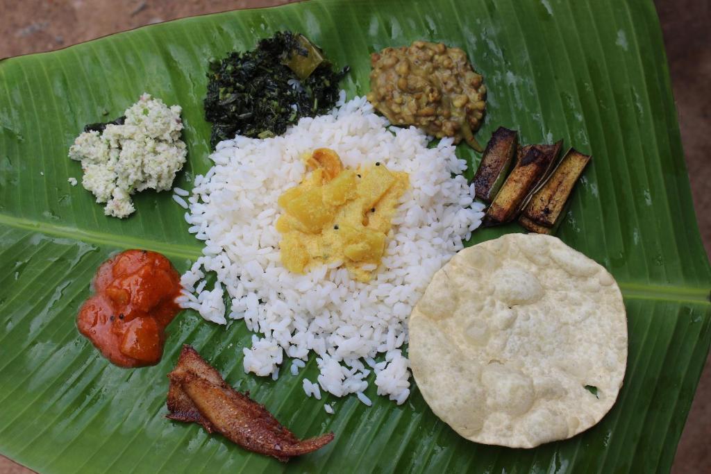 a plate of rice and other foods on a banana leaf at Uravu Bamboo Grove Resort in Wayanad