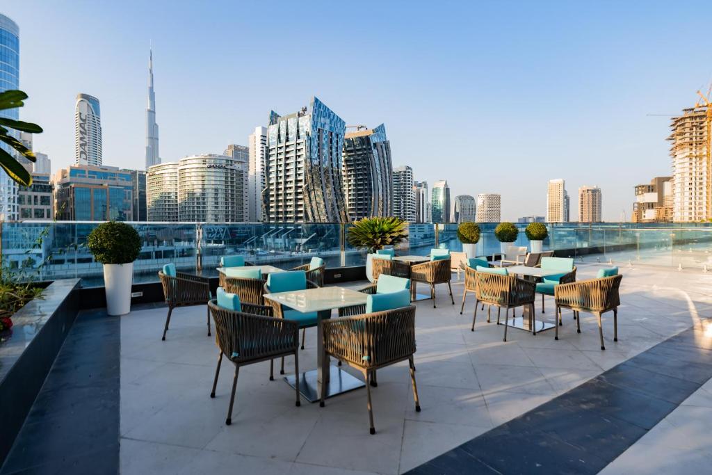 a patio with tables and chairs and a view of the city at Kasco Homes Waves Tower Business Bay in Dubai