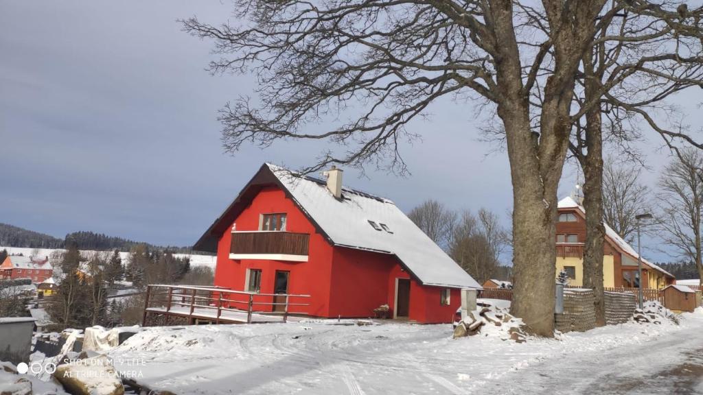 a red barn with snow on the roof at Apartmán u Drahotů in Pernink