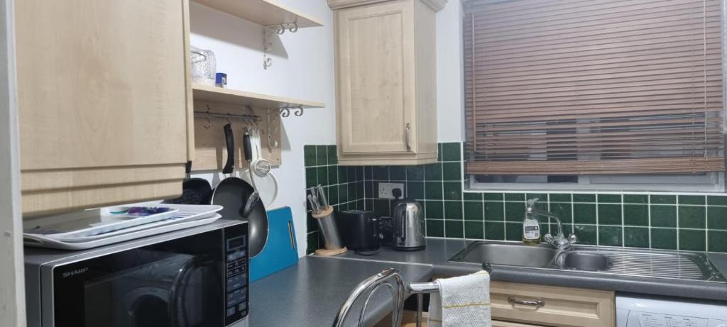 eine Küche mit einer schwarzen Mikrowelle und einer Spüle in der Unterkunft 2 Bedroom Apartment - Greater London in Dagenham