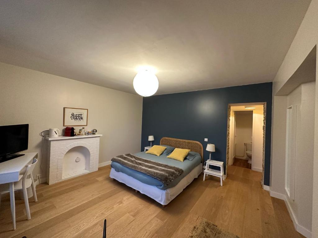 1 dormitorio con cama, chimenea y escritorio en La Pierre Percée en Vertou