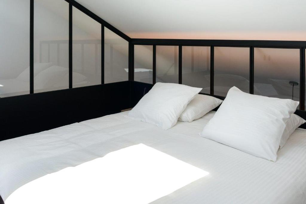 a bed with white sheets and pillows in a room at Le Florentin in Florenville