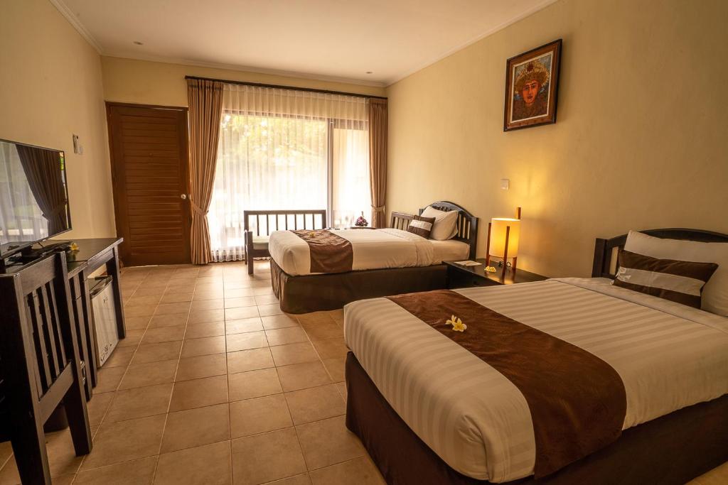 a hotel room with two beds and a television at New Sunari Lovina Beach Resort in Lovina