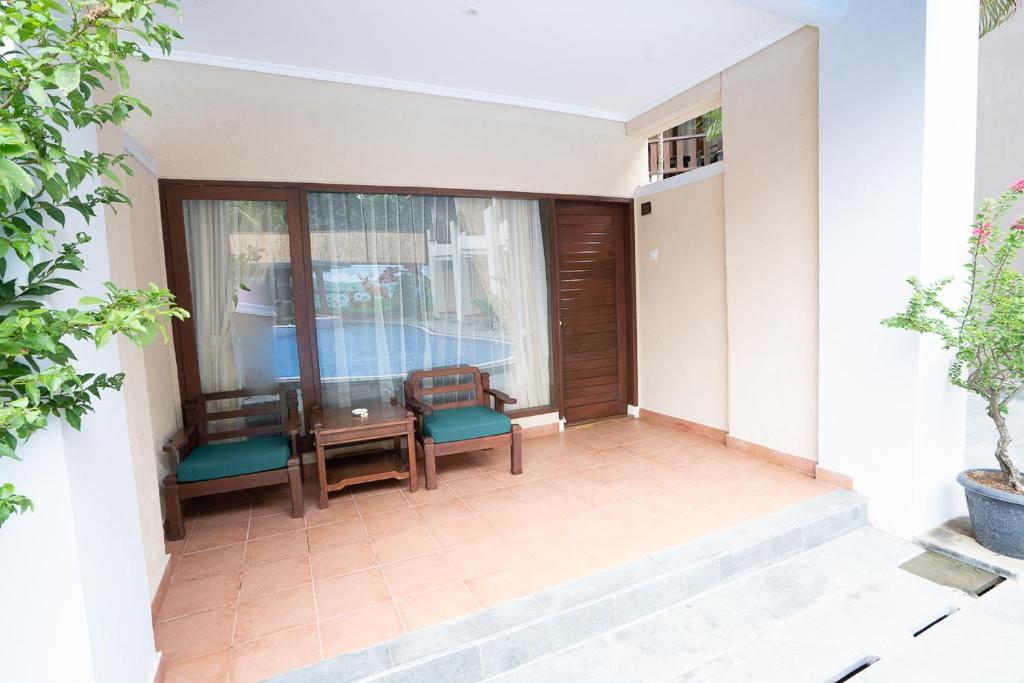 a balcony with a table and chairs and a window at New Sunari Lovina Beach Resort in Lovina