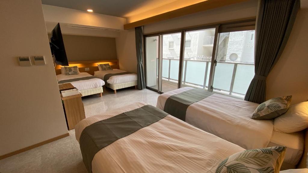 那霸Tabinoteitaku Okinawa Naha 2nd的有三张床和一扇窗户的酒店房间