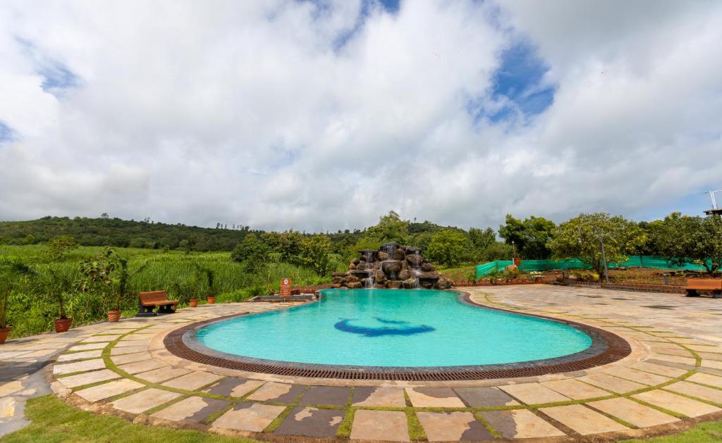 a swimming pool with a fountain in a yard at AATHAVAN MATICHI ECO RESORT in Panhāla