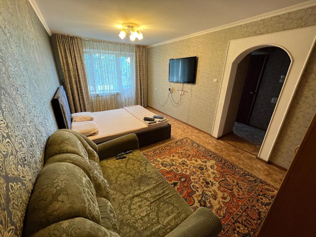 a hotel room with a couch and a bed and a television at Стандарт Камзина 74 г. Павлодар in Pavlodar