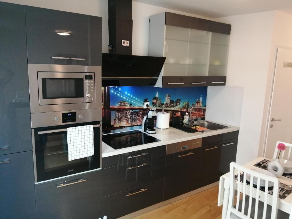 eine Küche mit schwarzen Schränken und einer Mikrowelle in der Unterkunft Apartment Tesla in Wien