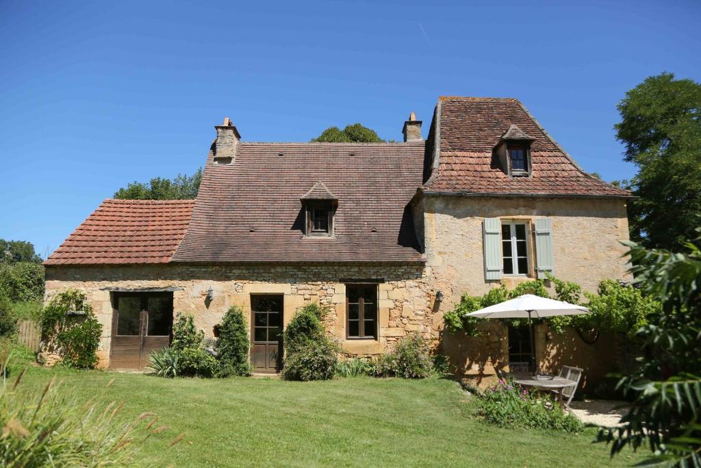 勒布格的住宿－La Maison de Jardin à La Peyrière，院子里带雨伞的古老石屋