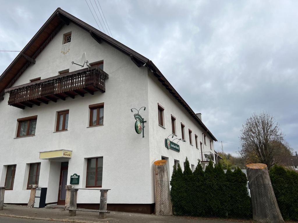 um edifício branco com uma varanda ao lado em Pension Hirsch em Fluorn