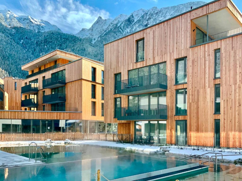 a building with a pool and mountains in the background at All-Suite Resort Ötztal in Oetz