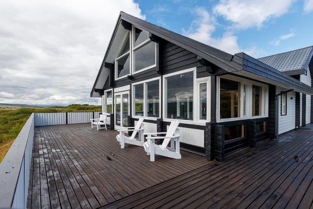 a house with white chairs on a wooden deck at Blue Viking Luxury Cabin in Selfoss