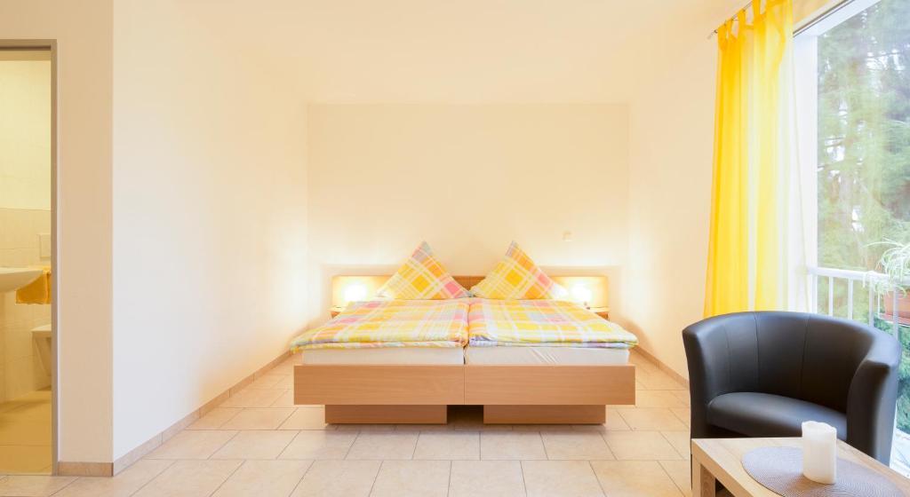 um quarto com uma cama, uma cadeira e uma janela em Haus Emona - Ihre Pension in Freiburg em Friburgo em Brisgóvia