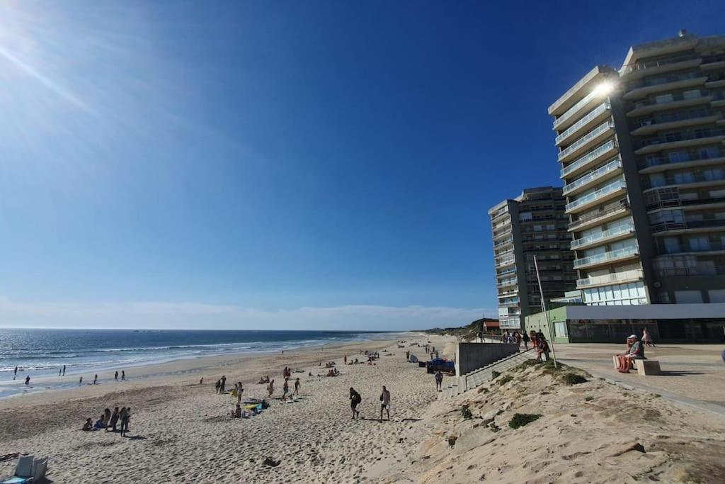 un grupo de personas en una playa al lado de un edificio en Ondas de Ofir, en Fão