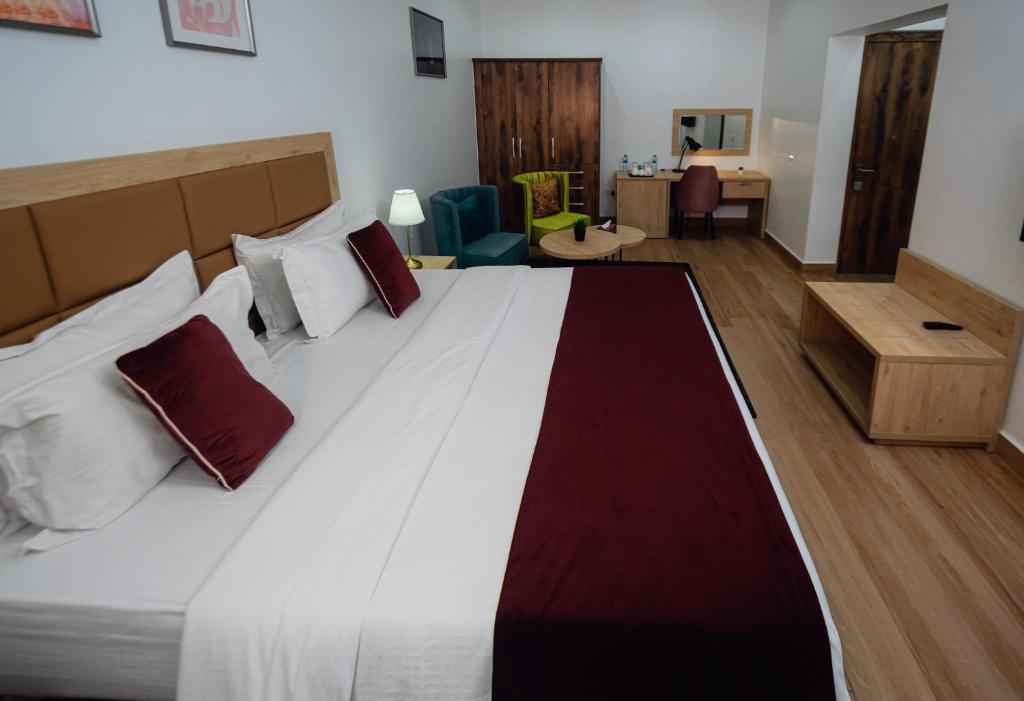 a bedroom with a large white bed with red pillows at Quest Boutique Hotel in Gwarinpa