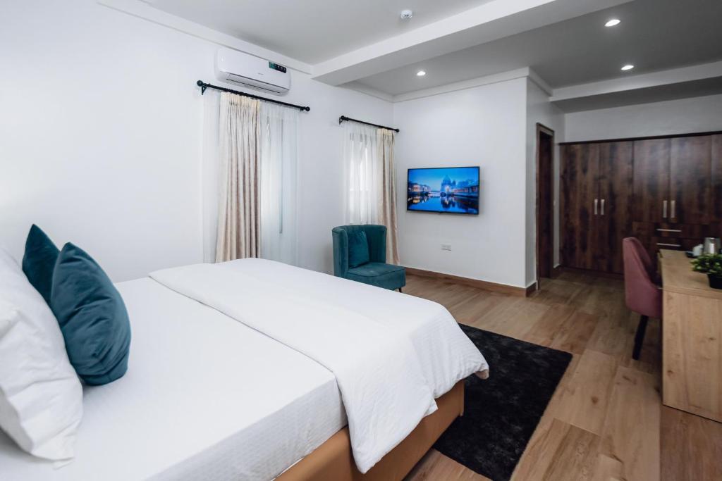 Schlafzimmer mit einem großen weißen Bett und einem Schreibtisch in der Unterkunft Quest Boutique Hotel in Gwarinpa