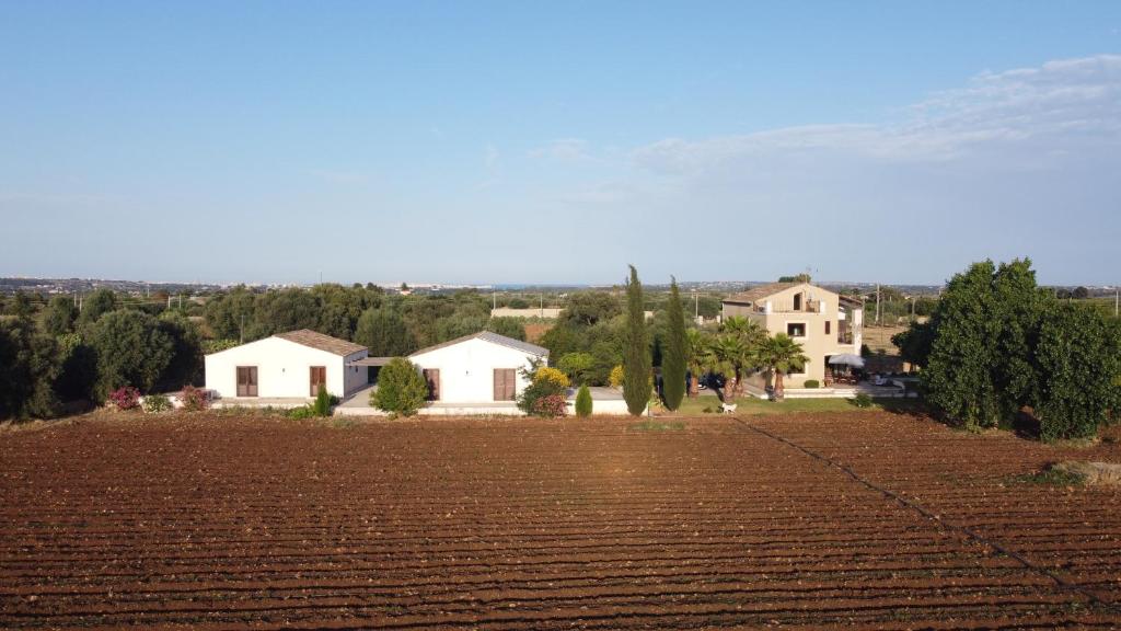 a large plowed field with houses in the background at Orecchie di Lepre in Siracusa